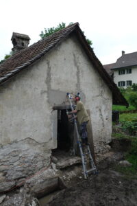 Restaurierung Waschhaus Lütishofer Chorhof, Beromünster LU. Claude Caviglia entfernt den harten Zementputz im Bereich des Türsturzes.