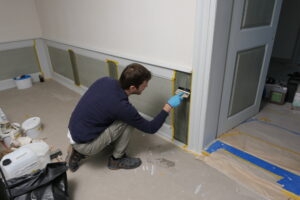 Rekonstruktion Dekorationsmalerei, Wohnhaus Sternenweg 9, Baar ZG. Der Restaurator fügt der aufgebrachten Ölfarbe mittels eines Borstenpinsel eine wellige Struktur zu.