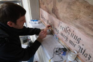 Musterrestaurierung Gemäldezyklus Hallenumgang, Klosteranlage Werthenstein LU. Florian Nick verfüllt Hohllagen mit verdünntem Sumpfkalk.